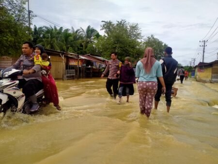 Personel Polsek Rantau Selamat Bantu Warga yang Kesusahan Melewati Genangan Air